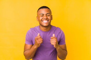Sarı arka planda izole edilmiş genç Latin bir adam mutlu ve başarılı hissediyor. Zafer konsepti.