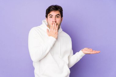 Mor arka planda izole edilmiş genç adam, avuç içinde kopya alanı tutmaktan etkilenmiş..