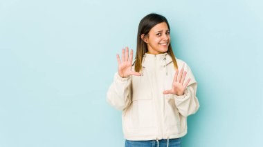 Mavi arka planda izole edilmiş genç bir kadın tiksinti gösteren birini reddediyor..