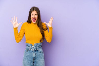 Mor arka planda izole edilmiş genç beyaz kadın gökyüzüne haykırıyor, yukarı bakıyor, hayal kırıklığına uğramış..