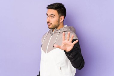 Mor arka planda izole genç beyaz adam iki ön parmağı da boş bir alan gösteriyor..