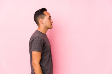 Yooung latin man posing in a pink backgroundgazing left, sideways pose. clipart