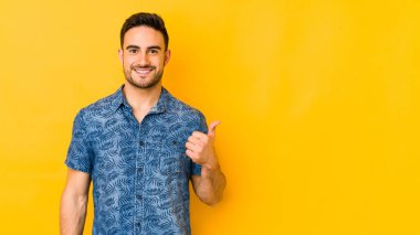 Sarı fırında izole edilmiş genç beyaz adam gülümsüyor ve başparmağını kaldırıyor.