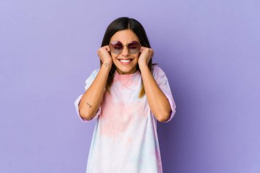 Mor arka planda izole edilmiş genç hippi kadın kulaklarını elleriyle kapatıyor..