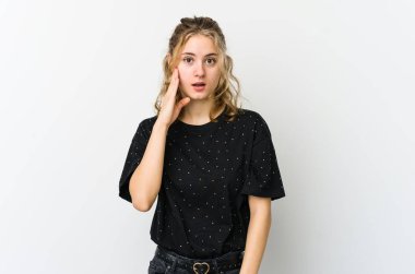 Beyaz arka plandaki genç beyaz kadın yüksek sesle bağırıyor, gözlerini açık ve ellerini gergin tutuyor..