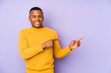 Mor arka planda izole edilmiş genç latin adam işaret parmağıyla fotokopi alanını göstererek şok oldu..