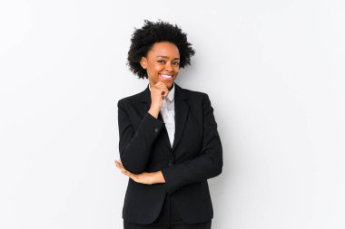 Orta yaşlı Afro-Amerikan iş kadını beyaz bir geçmişe karşı yalnız mutlu ve kendinden emin gülümseyen, elleriyle çenesine dokunan.