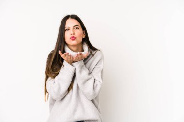 Beyaz arka planda izole edilmiş genç beyaz bir kadın dudaklarını katlıyor ve hava öpücüğü vermek için avuç içleri tutuyor..