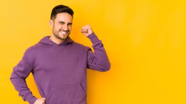 Sarı fırında izole edilmiş genç beyaz bir adam zaferi, tutkuyu ve coşkuyu kutluyor, mutlu bir ifade..