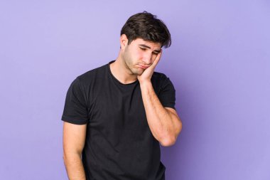 Mor arka planda izole edilmiş, sıkılmış, yorgun ve dinlenmeye ihtiyacı olan genç bir adam..