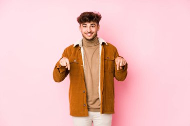 Pembe arka planda yalnız poz veren genç bir Arap.