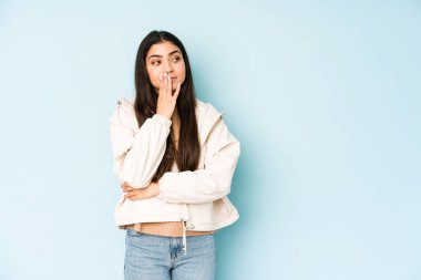 Mavi arka planda genç bir Hintli kadın esniyor. Ağzı eliyle kapatan yorgun bir jest gösteriyor..