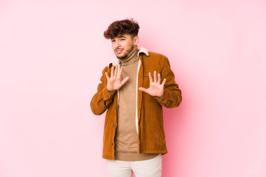 Pembe arka planda yalnız poz veren genç bir Arap.