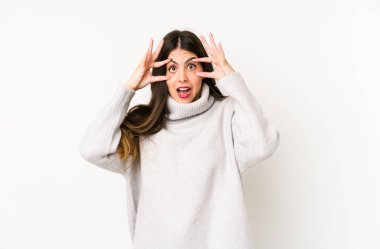 Beyaz arka planda izole edilmiş beyaz tenli genç bir kadın bir başarı fırsatı bulmak için gözlerini açık tutuyor..