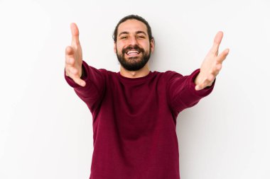 Beyaz arka planda izole edilmiş genç, uzun saçlı adam kameraya sarıldığı için kendinden emin hissediyor..