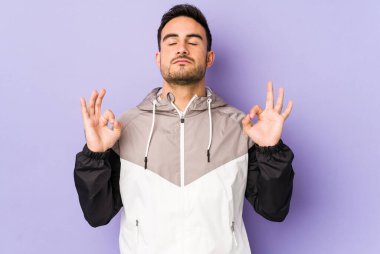 Mor arka planda izole edilmiş genç beyaz adam sıkı çalışma gününden sonra rahatlıyor. Yoga yapıyor..