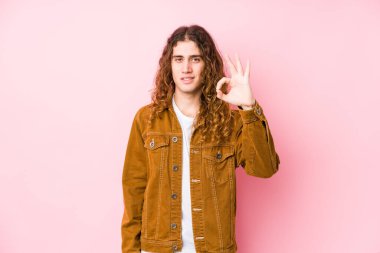 Genç, uzun saçlı, yalnız poz veren neşeli ve kendinden emin bir adam..