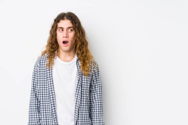 Genç, uzun saçlı bir adam gördüğü bir şey yüzünden şok olmuş gibi davranıyor..