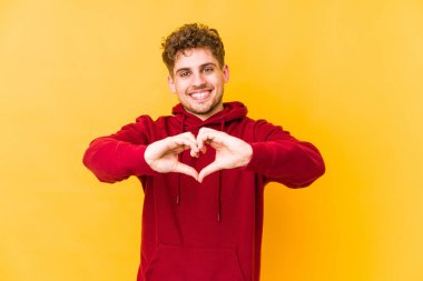  Gülümsüyor ve elleriyle kalp şeklini gösteriyor..