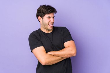 Mor arka planda izole edilmiş genç bir adam komik ve dost canlısı bir dil uzatıyor..