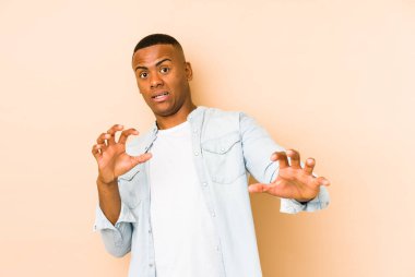 Bej arka planda izole genç latin adam yakın bir tehlike nedeniyle şoka uğruyor