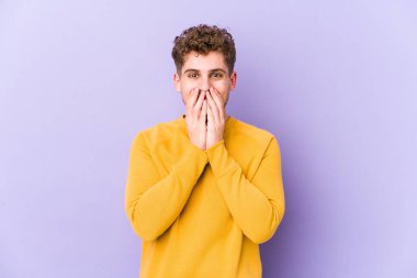 Sarışın, kıvırcık saçlı, beyaz tenli bir adam bir şeye gülüyor, ağızlarını ellerle kapatıyor..