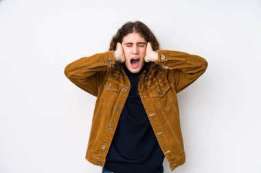 Uzun saçlı adam yalıtılmış poz veriyor. Kulakları elleriyle kapatıyor. Gürültülü sesler duymamaya çalışıyor..