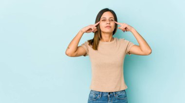 Mavi arka planda izole edilmiş genç bir kadın bir göreve odaklanmış, işaret parmaklarını işaret ediyor..