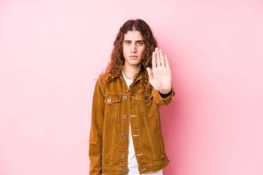 Genç, uzun saçlı bir adam, elini uzatmış yalnız poz veriyor, dur işareti gösteriyor, bu da seni engelliyor..