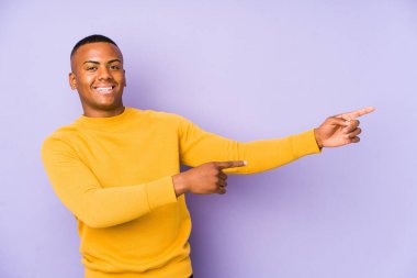 Mor arka planda izole edilmiş genç latin adam işaret fişeklerini göstererek heyecanlanıyor..