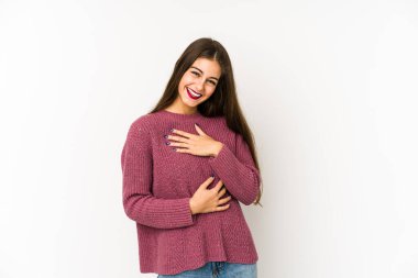 Beyaz arka planda izole genç beyaz kadın mutlu bir şekilde gülüyor ve ellerini karnının üstünde tutarak eğleniyor..