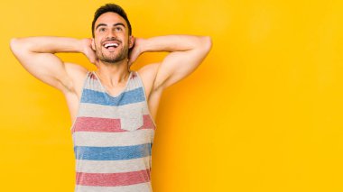 Kafkasyalı genç adam sarı fırında izole edilmiş. Kendine güveniyor, elleri başının arkasında..