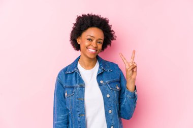 İki numarayı parmaklarıyla gösteren pembe bir sırt kaplamasına karşı genç Afrikalı Amerikalı kadın..