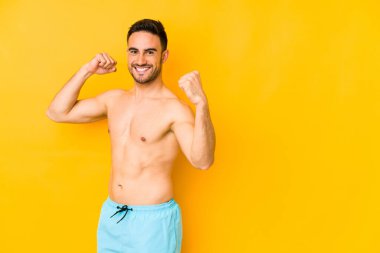 Sarı arka planda mayosu olan genç, beyaz bir adam. Kafkasyalı, tasasız ve heyecanlı bir genç. Zafer konsepti.