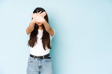 Mavi arka planda genç Hintli kadın iki kolu çapraz tutuyor, inkar kavramı.