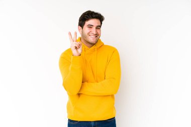 Genç adam beyaz arka planda iki numarayı parmaklarıyla gösteriyor..