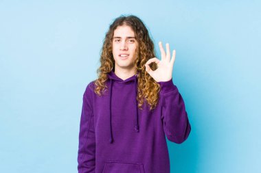 Uzun saçlı adam neşeli ve kendinden emin bir şekilde poz veriyor..