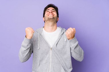 Mor arka planda izole edilmiş genç bir adam zaferi, tutkuyu ve coşkuyu, mutlu ifadeyi kutluyor..