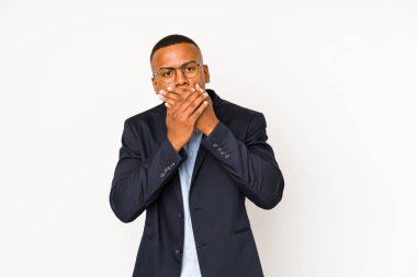 Beyaz arka planda izole edilmiş genç bir Latin adam elleriyle ağzını kapatırken şok oldu..