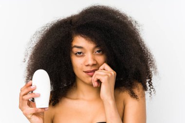 Elinde nemlendirici tutan genç afro kadın tırnak yiyor, gergin ve endişeli..