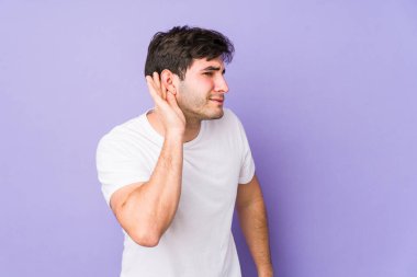 Mor arka planda izole edilmiş genç bir adam bir dedikoduyu dinlemeye çalışıyor..