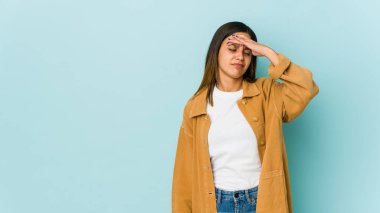 Mavi arka planda izole edilmiş genç bir kadın şakaklara dokunuyor ve başı ağrıyor..