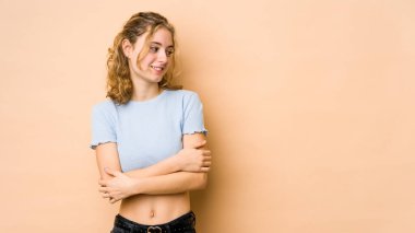 Bej arka planda izole edilmiş beyaz bir kadın. Kollarını kavuşturup gülümsüyor..