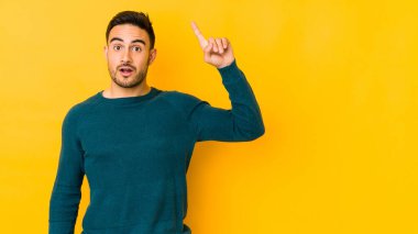 Kafkasyalı genç adam sarı fırında izole edilmiş, harika bir fikri var, yaratıcılık kavramı..