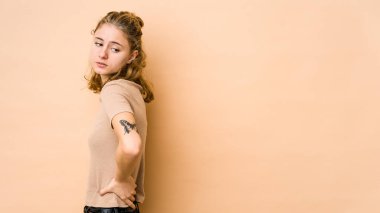 Bej arka planda izole edilmiş beyaz bir kadın sırt ağrısı çekiyor..