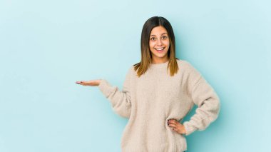 Mavi arka planda izole edilmiş genç bir kadın bir avuç içinde fotokopi alanı ve belinde bir el daha olduğunu gösteriyor..