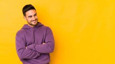 Sarı fırında izole edilmiş genç beyaz adam kollarını kavuşturarak gülümsüyor..