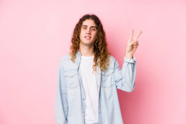 Uzun saçlı adam neşeli ve tasasız poz veriyor. Barış sembolünü parmaklarıyla gösteriyor..