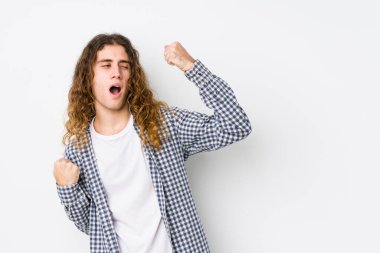 Genç, uzun saçlı adam poz veriyor. Zaferden sonra yumruğunu kaldırıyor. Kazanan kavram..