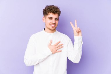 Sarışın, kıvırcık saçlı, beyaz tenli bir adam tek başına yemin ediyor ve elini göğsüne koyuyor..